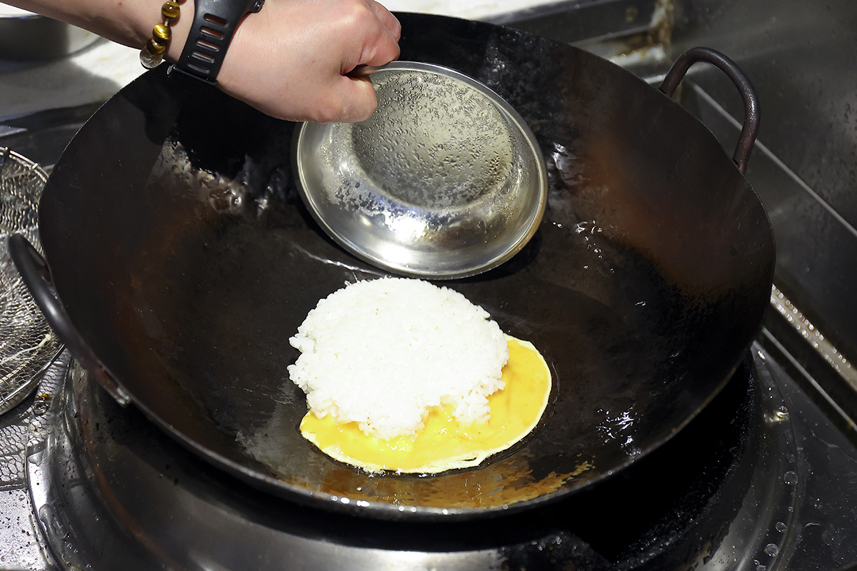 ①<br />
フライパンにサラダ油を入れ、強火にかけてよく熱したところに、溶きほぐした卵を入れ、すぐさまご飯を投入。卵とごはんがある程度まざったら中火にする。