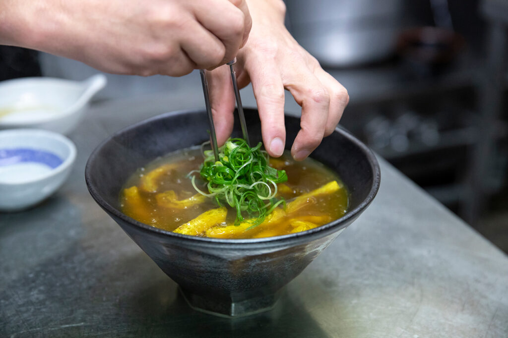 咖喱乌冬面带有海鲜汤和招牌菜[Ajika]香料的味道，这道菜自公司成立以来就一直出现在菜单上。