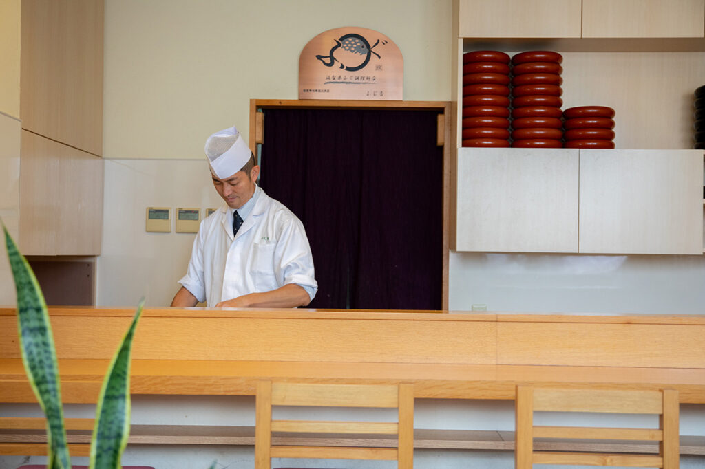 Owner Mr. Hirai standing at the counter of Fujiyoshi